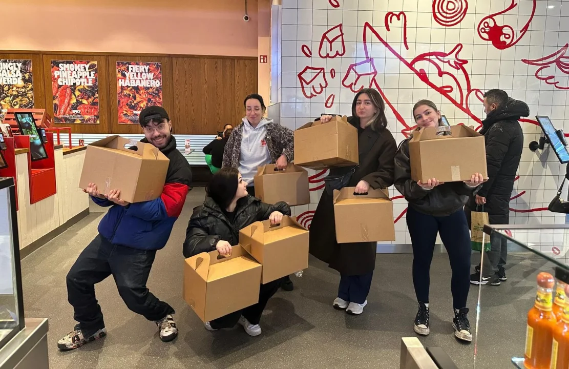 Salsa Shop team standing ready with catering boxes and bags outside the restaurant, preparing to deliver a fresh Mexican catering order for a company or event.