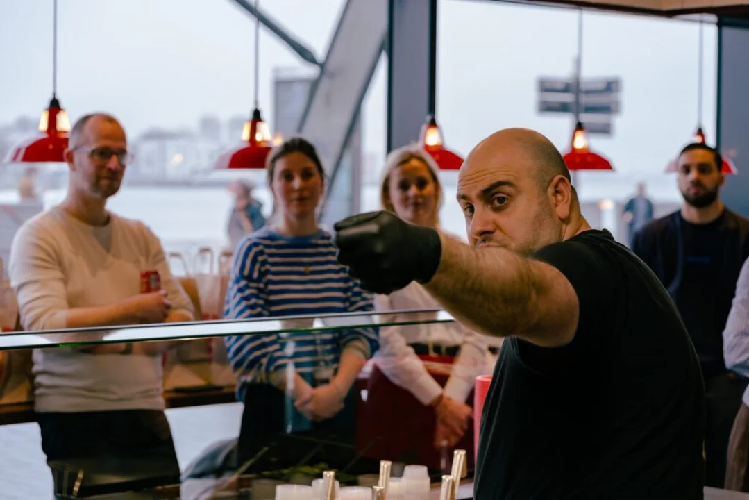 Salsa Shop COO Alex explaining the cooking process to a group of influencers and media during a behind-the-scenes cooking workshop in the restaurant kitchen.