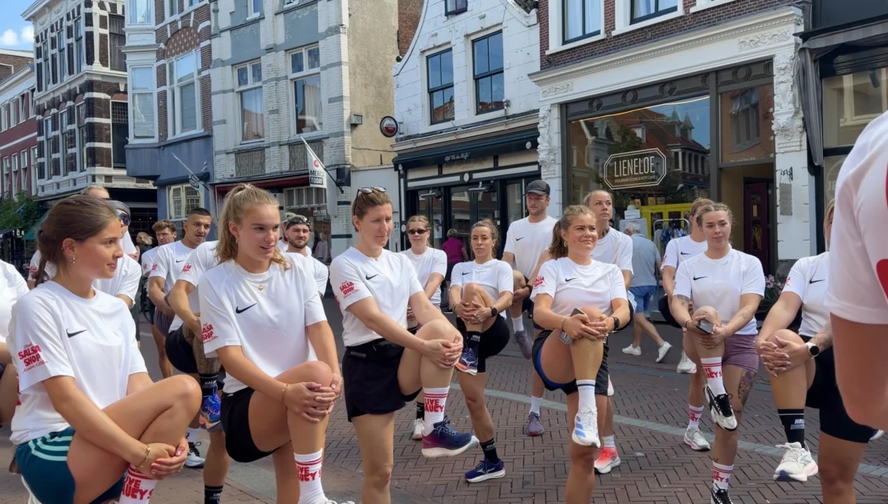 Salsa Shop Run Club in Haarlem in collaboration with HRLM Running, with participants wearing Salsa Shop x Nike sportswear and Live Saucy socks during a warm-up in Haarlem city centre.