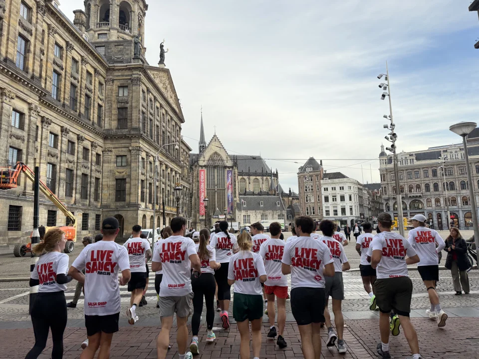 Live Saucy Run Club runners crossing Dam Square in Amsterdam early in the morning.